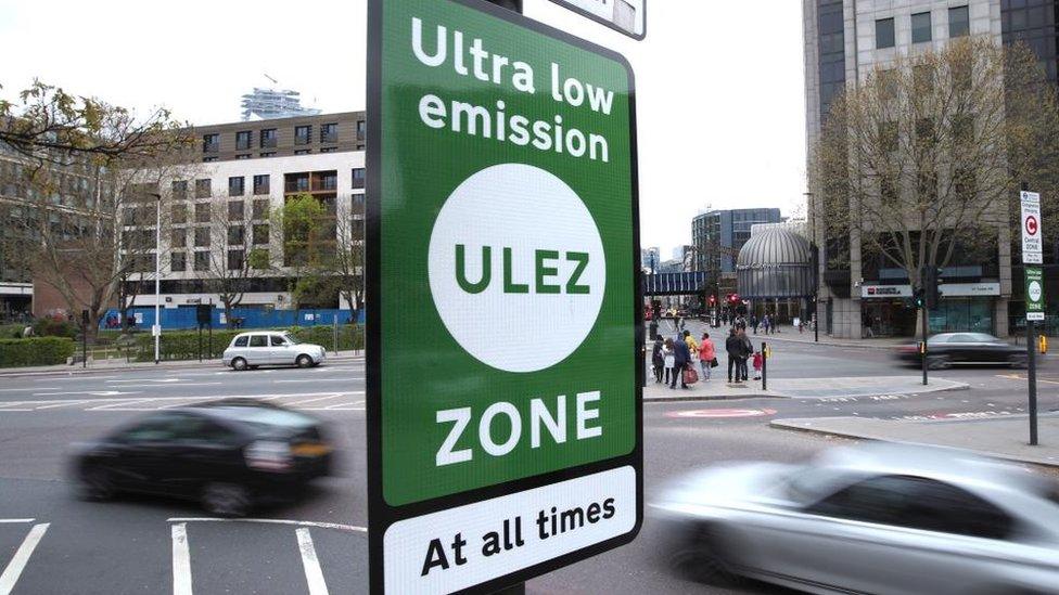 A file photo shows a sign for the Ulez scheme. In the background, cars can be seen going by on a busy road in London.