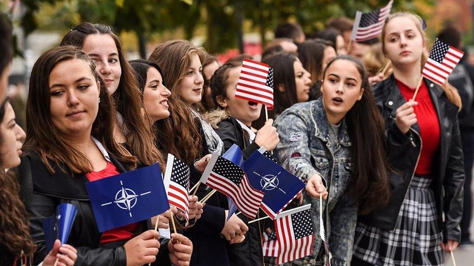 Kosovo Albanian youth wave US and NATO flags during a US Army and Kosovo Security Force running competition in Pristina on October 20, 2016. Approximately 4,600 troops from the NATO-led Kosovo Force (KFOR), provided by 31 countries are still present in Kosovo