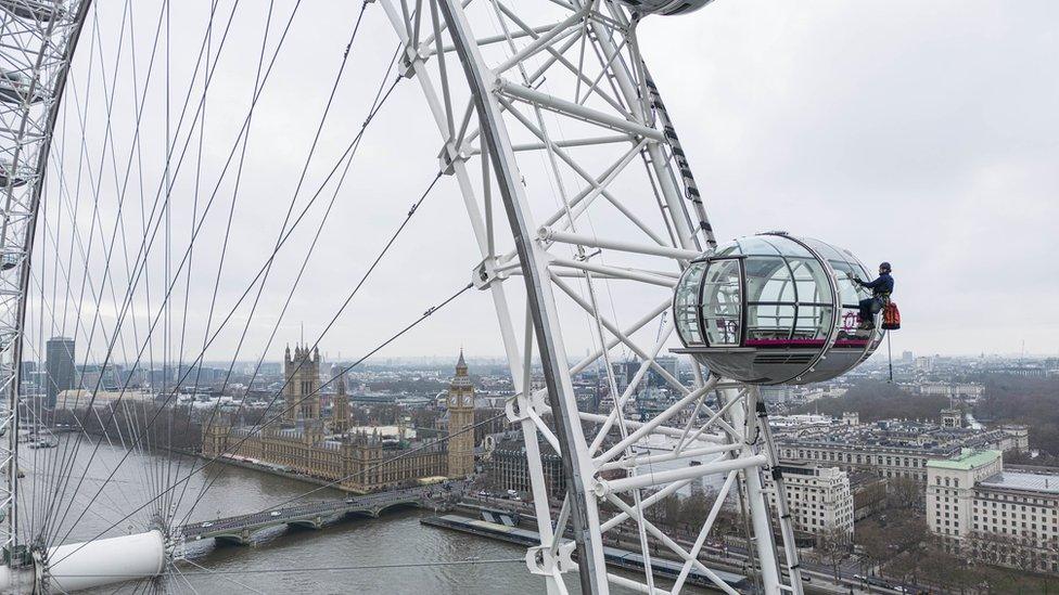 A window cleaner scrubs the London Eye pods