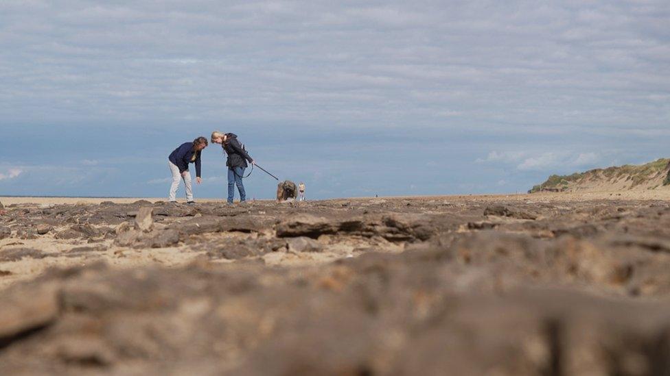 Two people looking at the mud on Formby Beach