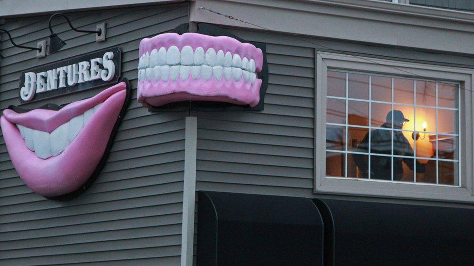 A Halifax regional police investigator is seen in a suite above the Atlantic Denture Clinic April 20, 2020