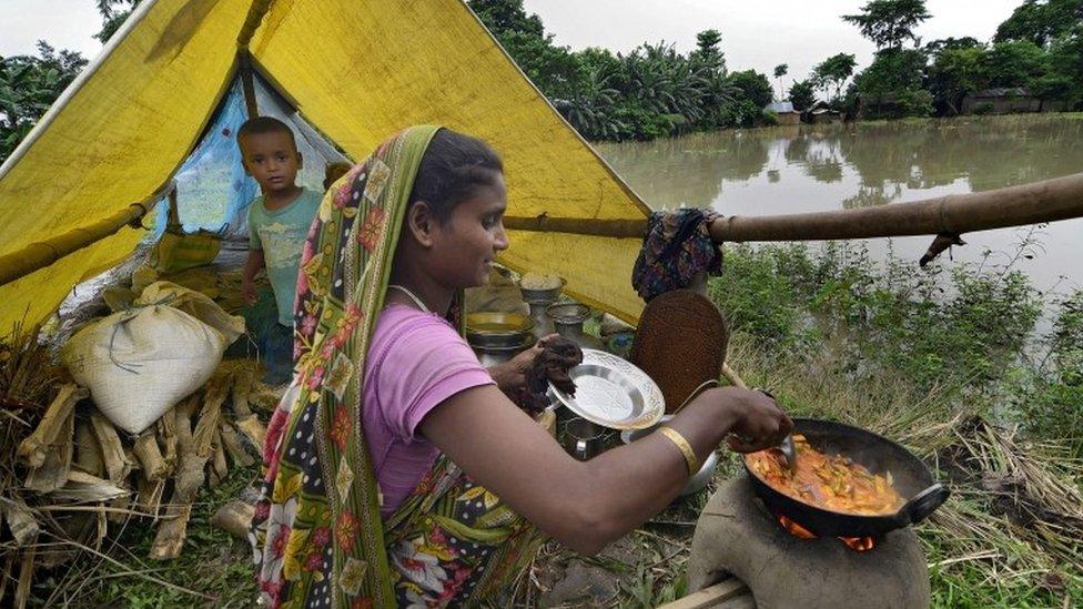 A woman prepares food as her boy looks on in a relief camp in the flood affected Morigaon district of Assam state, India, 02 September 2015