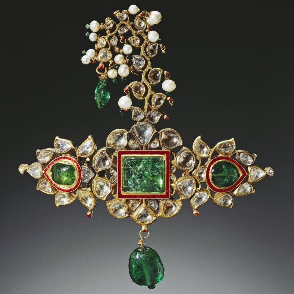 A turban ornament made of three large emeralds and bordered by bands of bright red enamel and diamonds. The sirpech came from the treasury of Sajjan Singh, Maharaja of Udaipur.