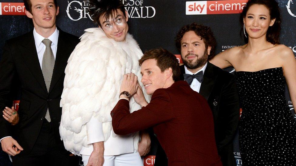 Eddie Redmayne playing with Ezra Miller's outfit