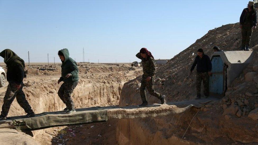 Syrian Democratic Forces (SDF) fighters cross a makeshift bridge in northern Deir al-Zor province, Syria on 21 February 2017.