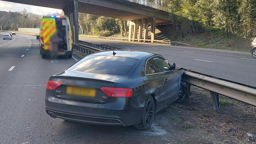 Car crashed into the central reservation and a emergency van parked a few metres in front of the car