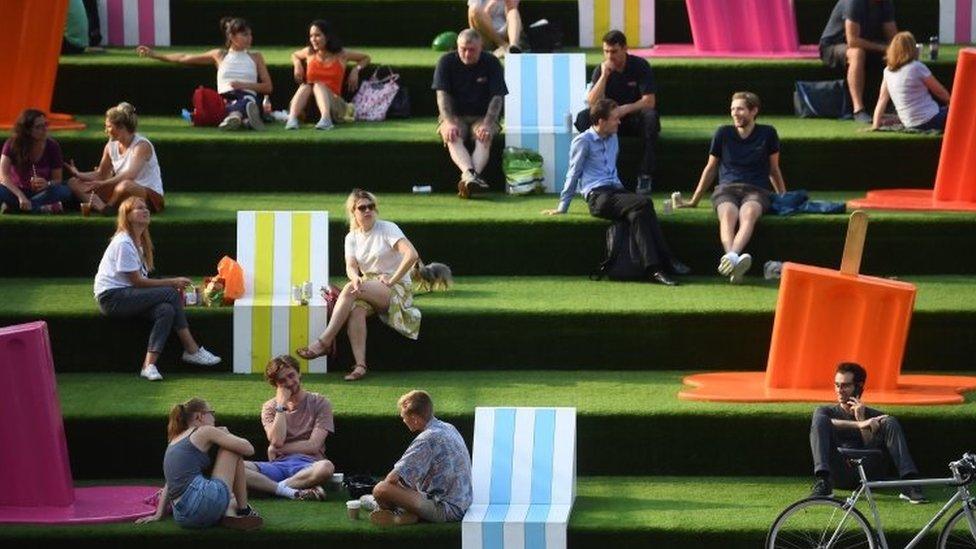 People on the steps near Granary Square in King's Cross, London, as the warm weather continues