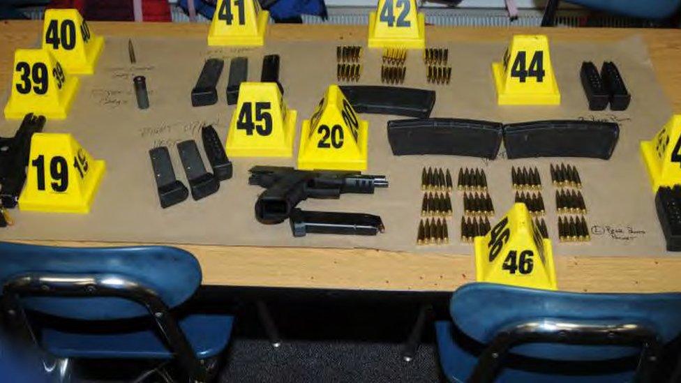 Dozens of items of weapons and ammunition are pictured on a table