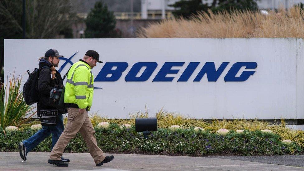 A pair of workers walk past a Boeing sign