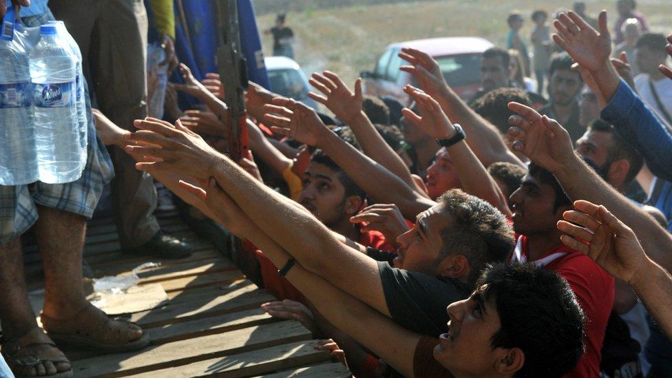 Migrants reach for bottled water at Idomeni, Greece, near Macedonian border