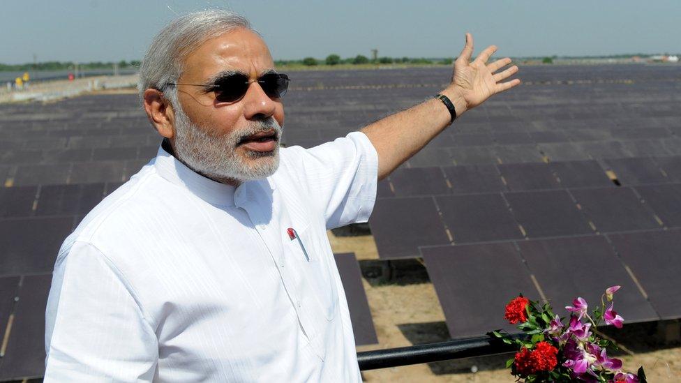 Narendra Modi gestures as he poses at the inauguration of a solar farm in the village of Gunthawada, Banaskantha district