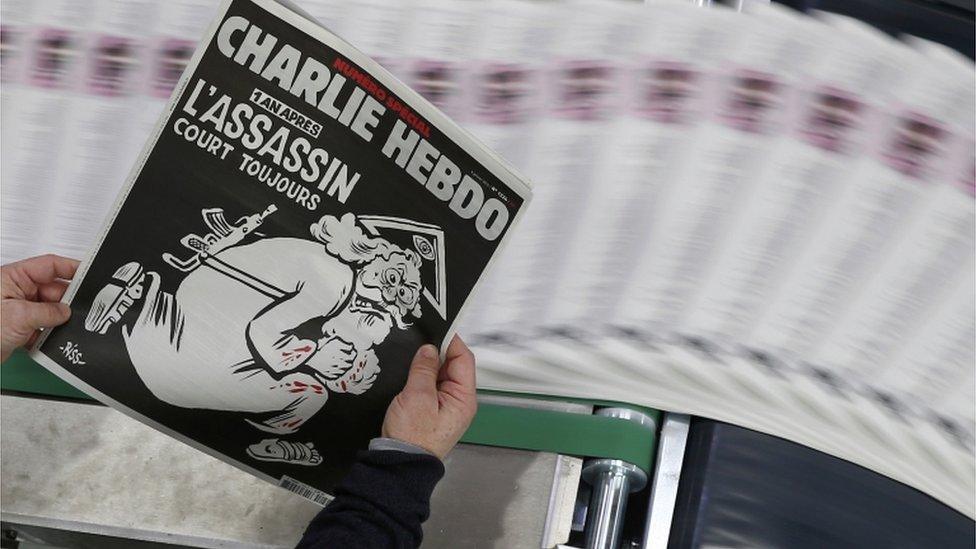 Charlie Hebdo front cover depicts God carrying a gun under the headline: "One year on: The assassin still at large."