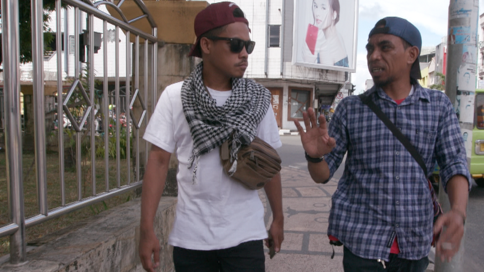 Ronald and Iskandar walk down the street, talking together