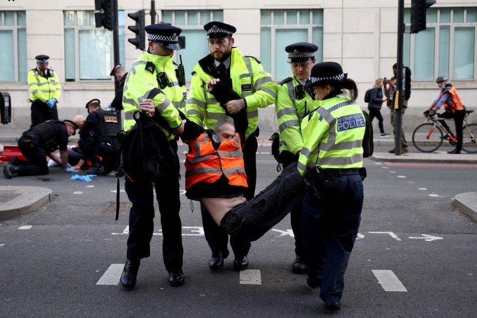 Police officers carry an Insulate Britain activist during a protest in London