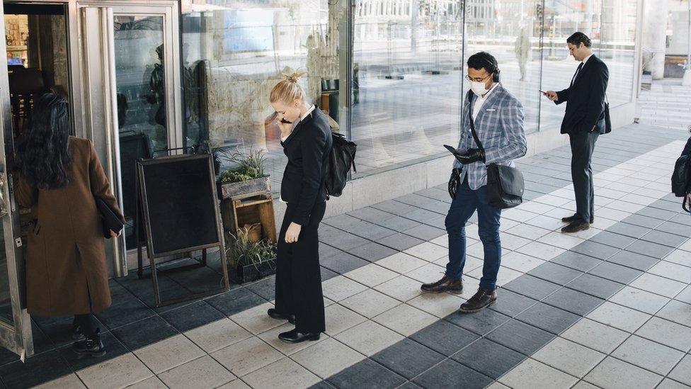 stock photo of people socially distancing outside a shop