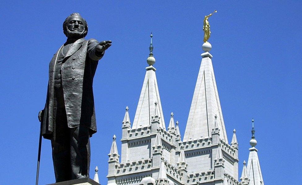 A statue of Brigham Young, second president of the Church of Jesus Christ of Latter Day Saints stands in the center of Salt Lake City with the Mormon Temple spires in the background