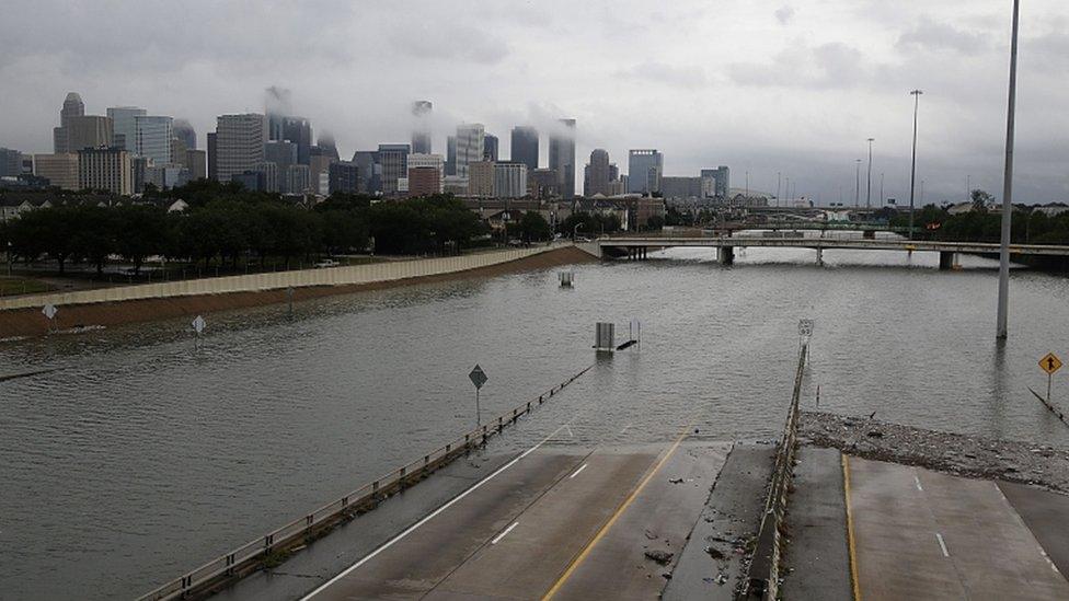 A whole road is pictured submerged with Houston skyline in the distance