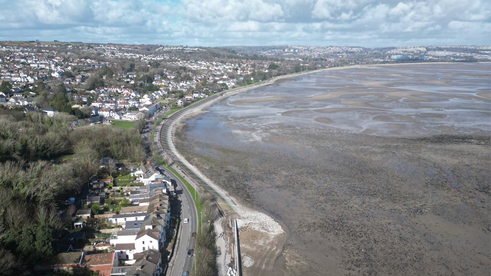 An aerial view of Swansea, with water on the right and numerous houses in Swansea on the left 