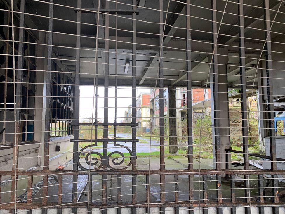 A view inside factory grounds through an old gate and fencing