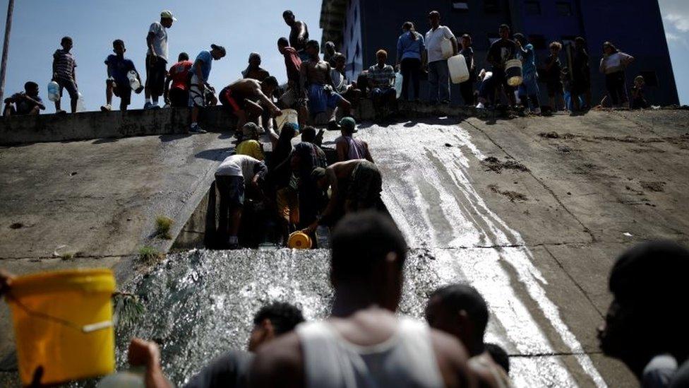 People collect water released through a sewage drain that feeds into the Guaire River, which carries most of the city's wastewater, in Caracas, Venezuela March 11, 2019.