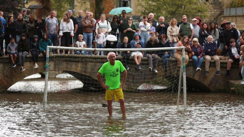 A man standing in a goal in a river