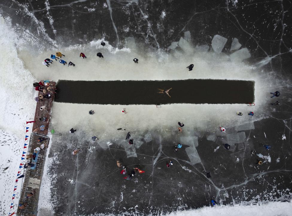 A woman swims in the icy waters of the Irtysh River on the opening day of the winter swimming season in Omsk, Russia, 5 December 2021.