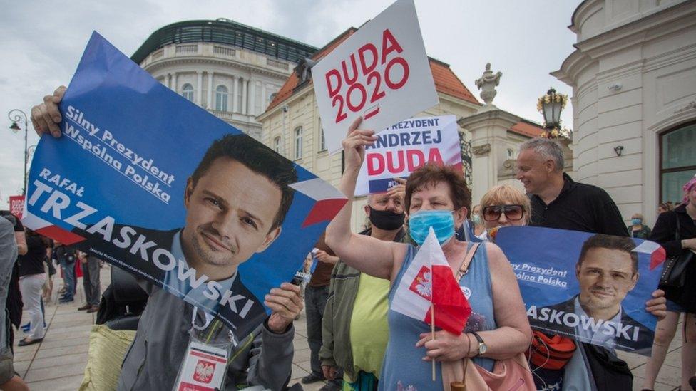 Supporters of President Andrzej Duda and his rival Warsaw mayor Rafal Trzaskowski hold placards during a presidential election campaign event in Warsaw, Poland, June 26, 2020