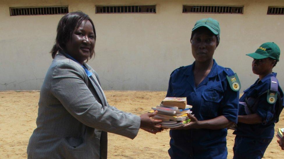 Woman hands books to prison guard