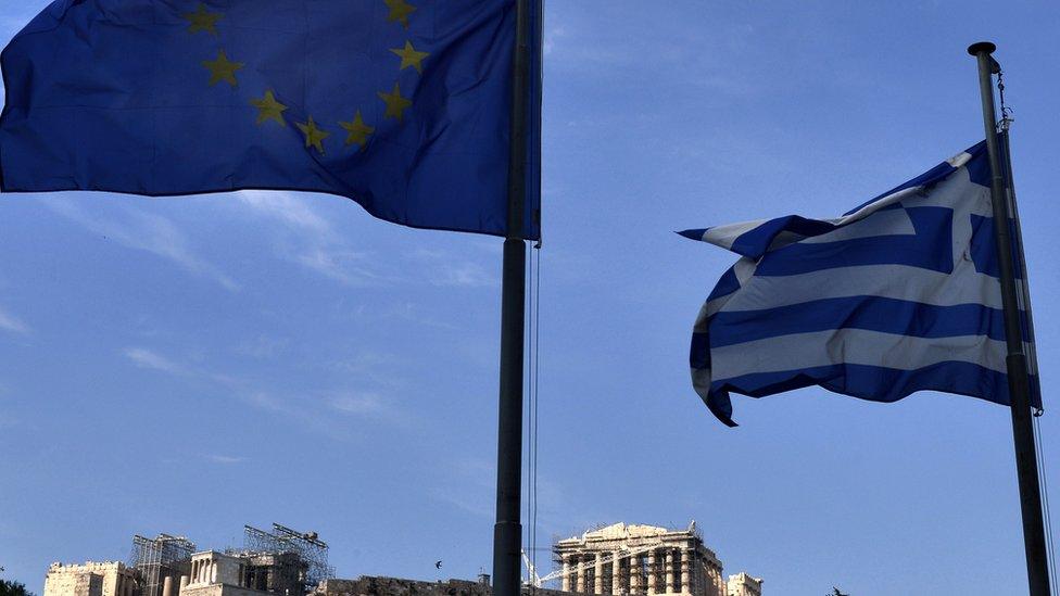 European Union and Greek flags flutter in front of the Acropolis hill in central Athens on 26 June 2015.