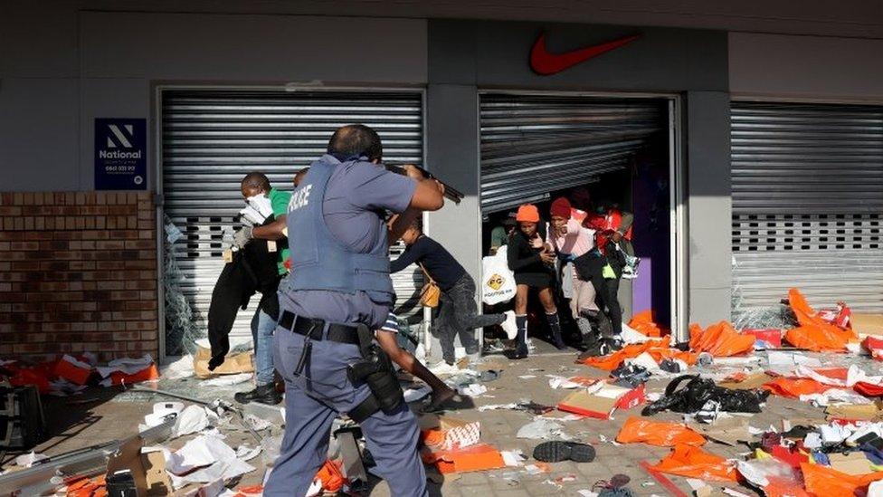 A member of the South African Police Forces tries to control looting during protests in Durban