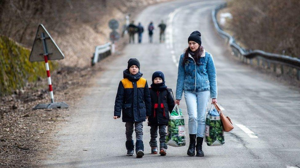 Woman walking with two children, in big coats