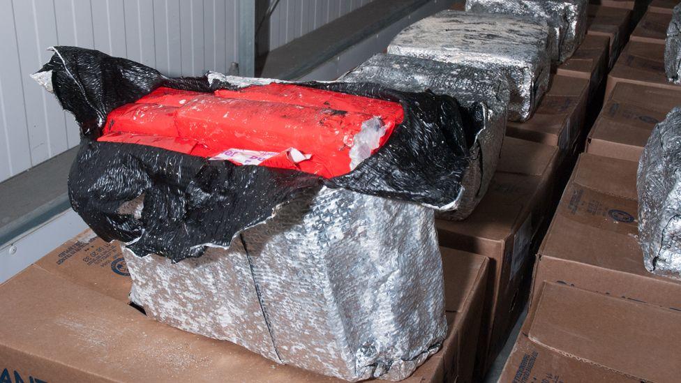 A silver package opened at the top to show a large block of cocaine inside a red packet