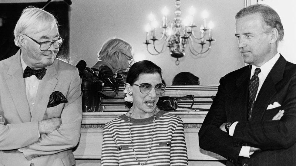 Supreme Court nominee Ruth Bader Ginsburg answering reporter's questions during courtesy call to Senator Joe Biden's office. She's standing with Sens. Biden and Daniel Patrick Moynihan 15 June, 1993