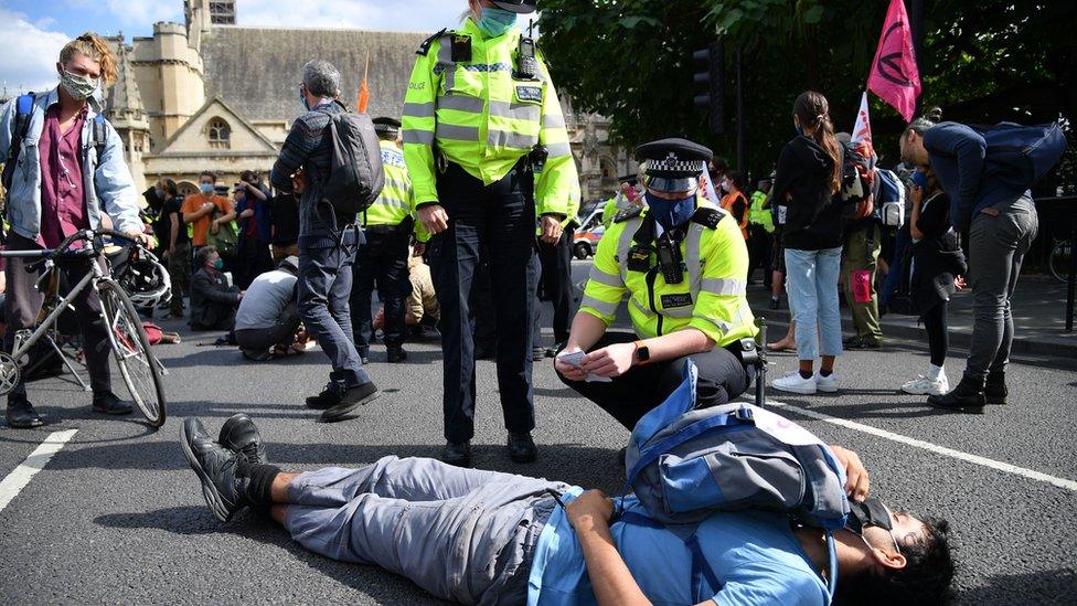 An activist is spoken to by police officers