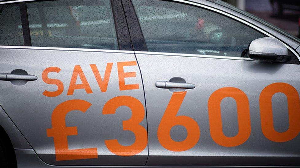 A sign advertises discounts on new cars for sale