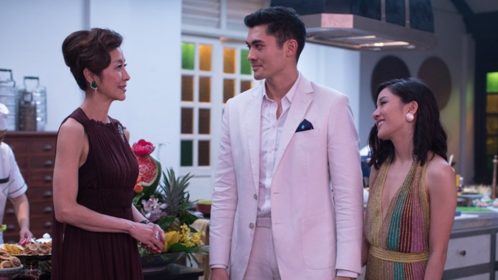 Movie still from Crazy Rich Asians showing Michelle Yeoh, Henry Golding and Constance Wu smiling at one another