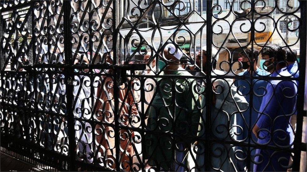 People wait outside a mosque to offer Friday congregational prayers despite a complete lockdown of the Sindh province in Karachi, Pakistan, 27 March 2020