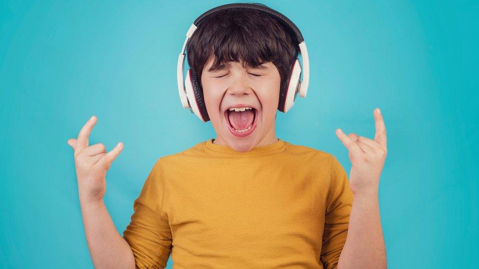 A boy listening to headphones on a blue background