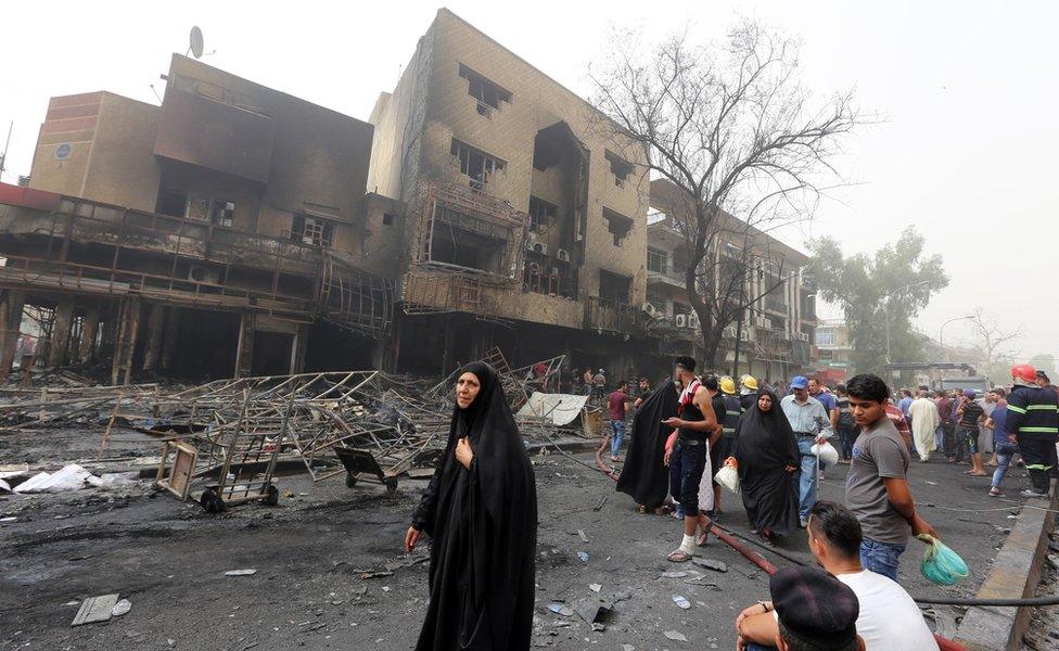 Iraqis, including firefighters, gather at the site of a suicide car bombing claimed by the Islamic State group on July 3, 2016 in Baghdad"s central Karrada district.