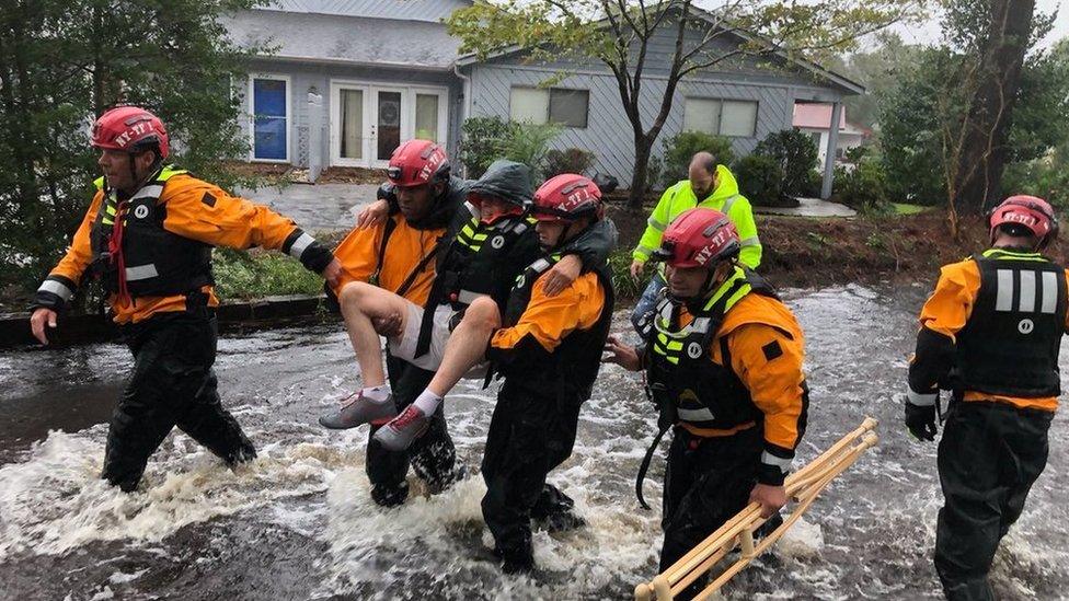 Rescue workers carry a man away from flooding in River Bend, North Carolina (14 September)