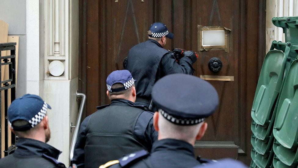 Officers use a battering ram to break down a door