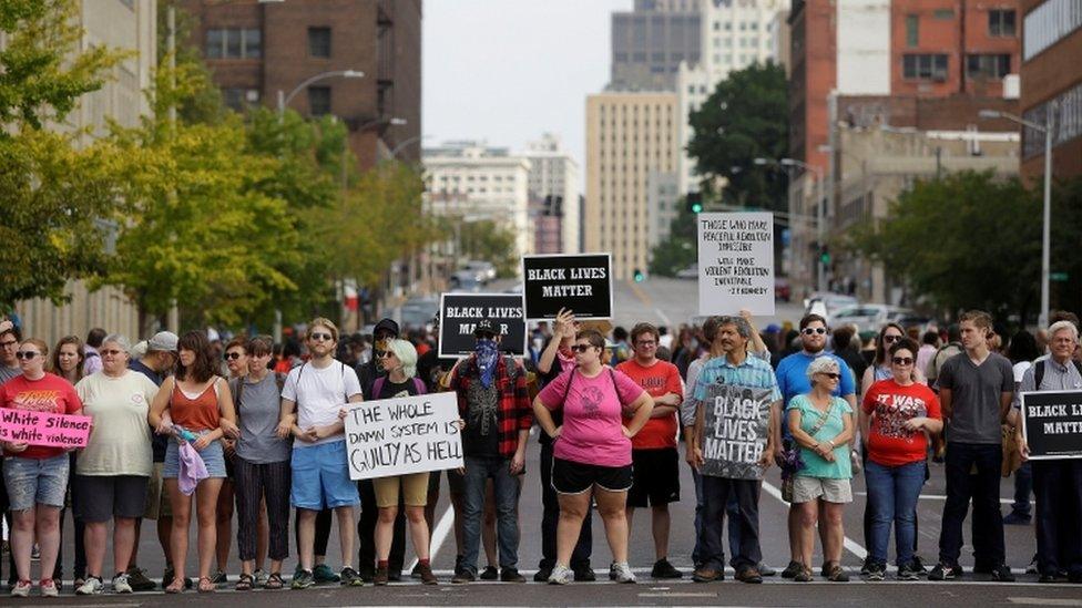 A group of peaceful protestors link arms holding 'Black lives matter' signs