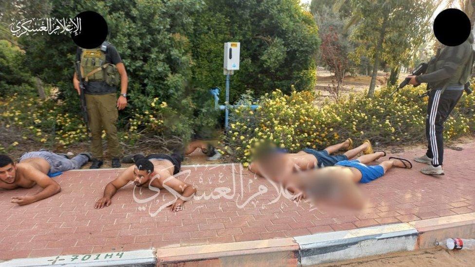 A photo posted by Hamas after the 7 October attack on Israel showing Bilal and Hamza Zyadna lying on their stomachs, with two Thai national nearby, as two armed men stand next to them