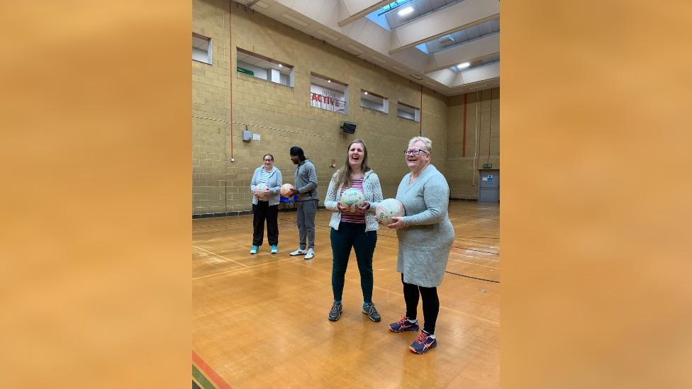 Four people talking in pairs and holding netballs