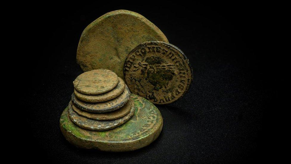 a group of coins stacked together - one coin has words written in latin and a picture of a roman