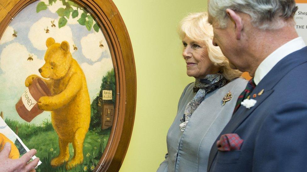 Prince Charles and the Duchess of Cornwall admire a painting of Pooh