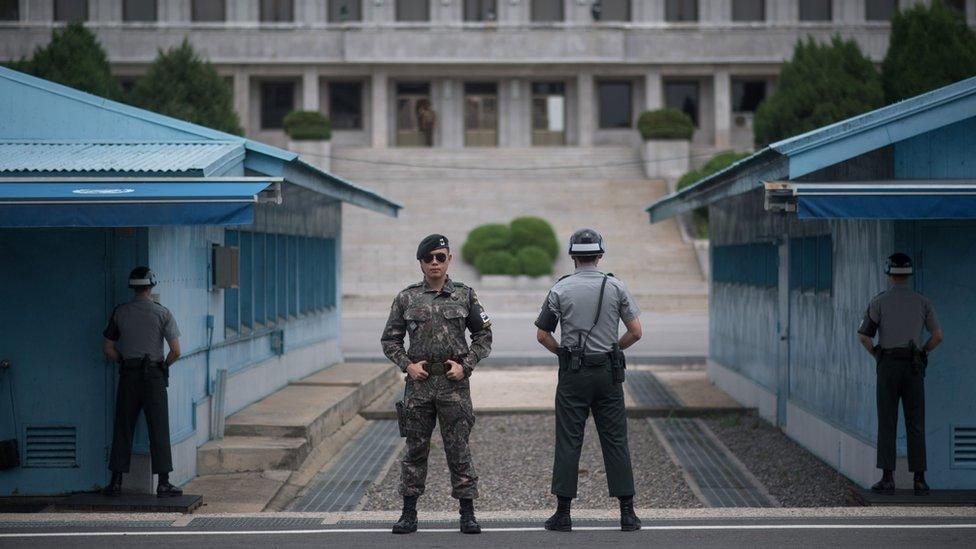 In a photo taken on August 2, 2017 South Korean soldiers stand guard before North Korea"s Panmon Hall (rear C) and the military demarcation line separating North and South Korea, at Panmunjom, in the Joint Security Area (JSA) of the Demilitarized Zone (DMZ).