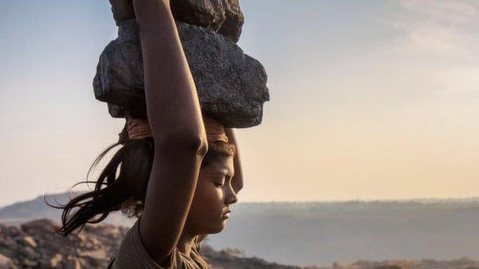 A woman carries coal on her head while working in the Jharia coal field in Jharkhand