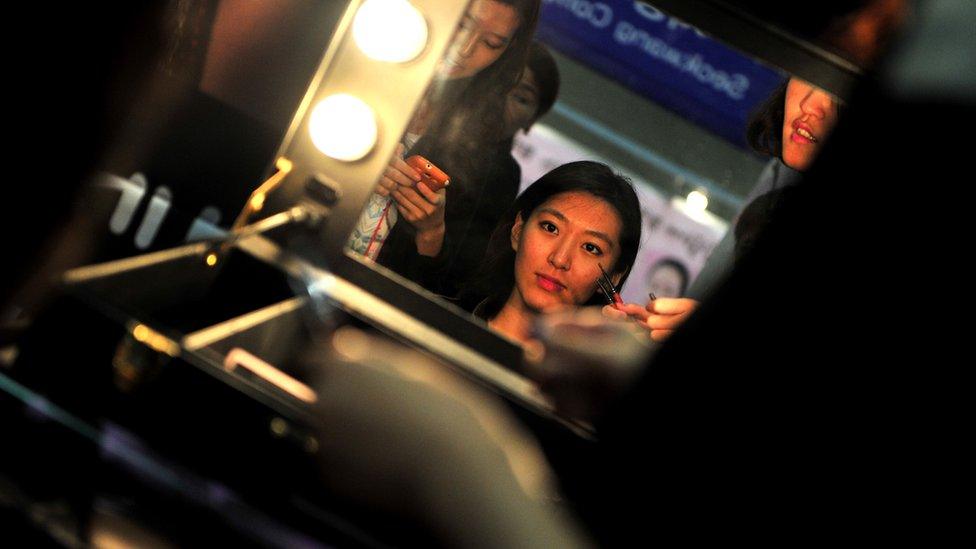 A customer (C) is attended to by a make-up artist (R) during the 5th Korea Beauty and Cosmetic Expo in Goyang, north of Seoul on September 14, 2013