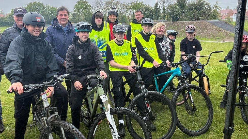 A group picture of people standing with bicycles at the track